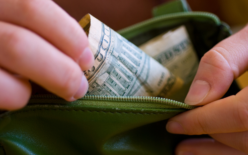 woman pulling money out of green wallet