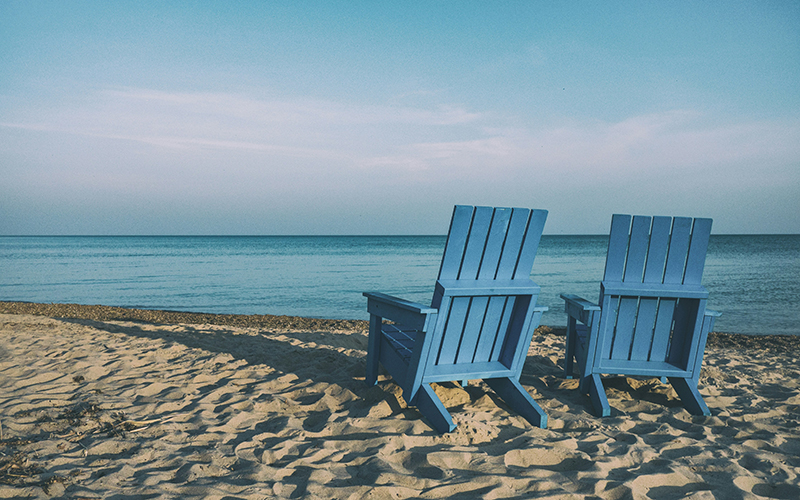 two blue chairs on a beach