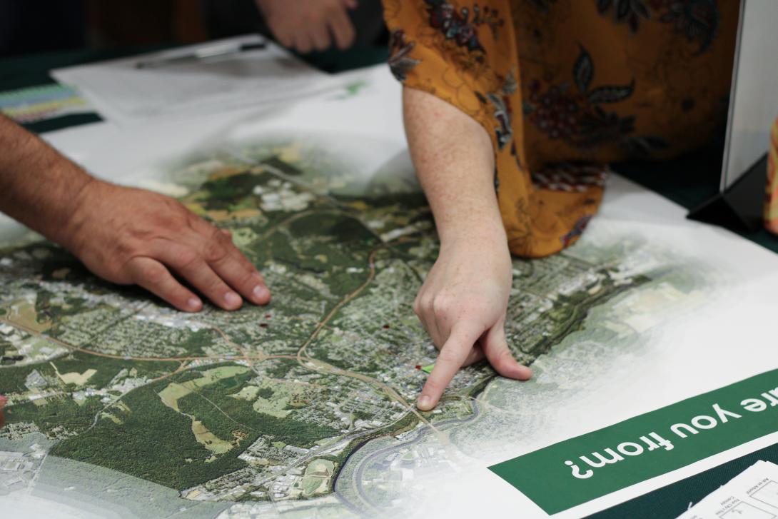 A close up photo of a person pointing on a map of a city with another persons hand resting nest to theirs